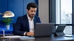 Homem de terno sentado em uma mesa de escritório moderno, trabalhando com notebook e tablet, enquanto analisa informações sobre o cálculo de férias e 13° salário no contrato intermitente com foco. Ambiente corporativo com luz natural ao fundo.